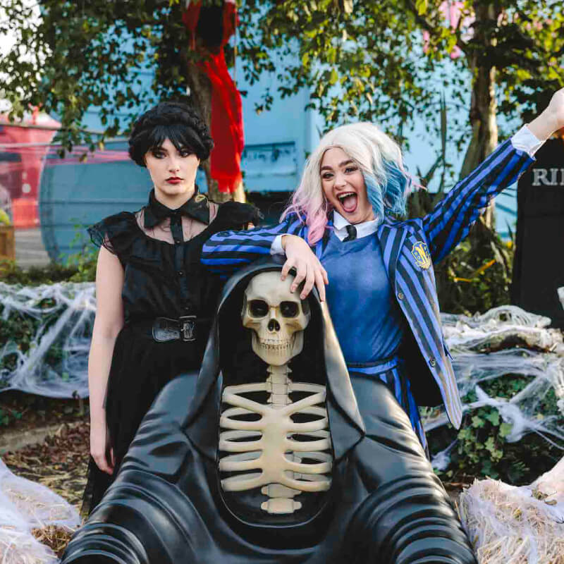 2 performers standing with a hooded skeleton